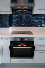 Modern black induction stove. Energy efficient electric hob with built-in oven at home kitchen ....