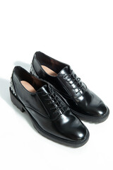 Fashionable female black leather shoes with silver details isolated on a white background.