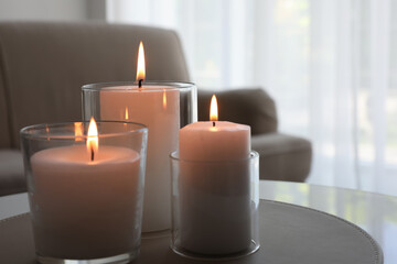 Burning candles in glass holders on table indoors. Space for text