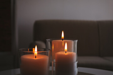 Fototapeta na wymiar Burning candles in glass holders indoors, closeup