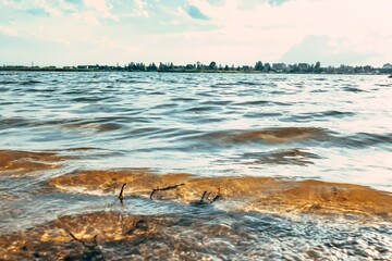 Obraz premium Waves of the city lake with dirty yellow water. Bathing is forbidden.