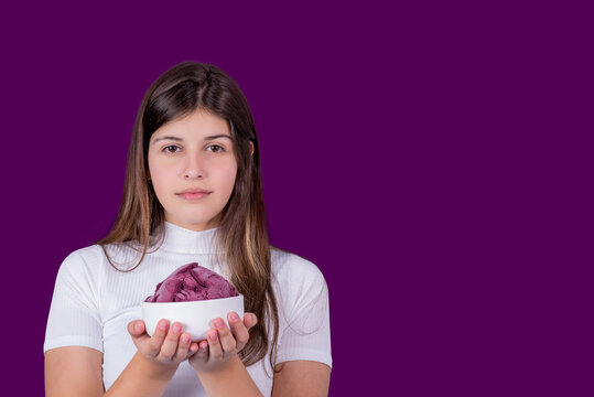 woman in white clothe isolated over purple background holding acai ice cream with pleasure. Dieting concept.
