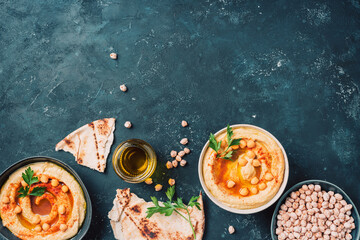 Chickpeas hummus, olive oil, raw chickpeas, smoked paprika, pita on dark background. Middle...