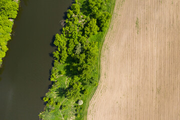 Empty agricultural field near the river prepared for sowing seeding in spring, aerial drone top view