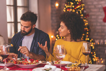 Couple speaking to each other at Christmas dinner