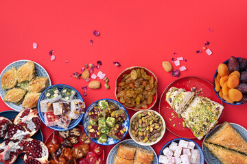 Middle Eastern sweets on red background. Arab dessert, baklava, halva, rahat lokum, sherbet, nuts, pistachios, dates, raisins, dried apricots, churchkhela, cookies. Top view. Flat lay. Copy space