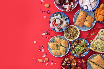 Middle Eastern sweets on red background. Arab dessert, baklava, halva, rahat lokum, sherbet, nuts,...