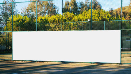 large blank white poster with mockup space hanging on metal fence of play ground