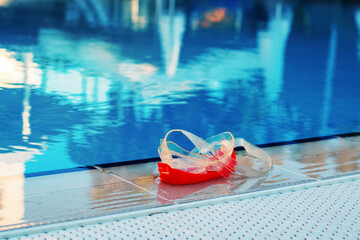 red swimming mask or goggles on board of hotel pool with blue water