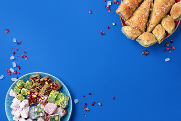 Middle Eastern sweets on blue background. Arab dessert, baklava, halva, rahat lokum, sherbet, nuts,...