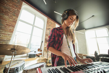 Talented musician, beautiful woman recording music, singing and playing piano while standing in loft workplace or at home. Concept of hobby, music, art and creation. Creating first single. - Powered by Adobe