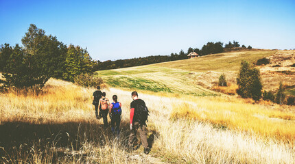 Rear view of unrecognizable people with backpack hiking in the n