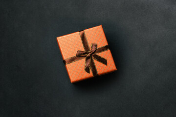 Gift box with ribbon on a dark background. Brown holiday packaging for birthday, Christmas, wedding and other festive event. top view of a flat layout