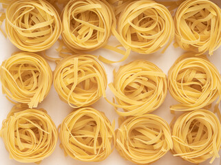 Uncooked dry tagliatelle pasta nest. On white background.