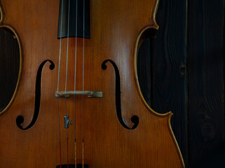 Fragment of a beautiful cello or violin on a wooden background with place for text