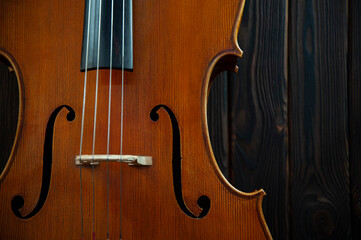 Fragment of a beautiful cello or violin on a wooden background with place for text