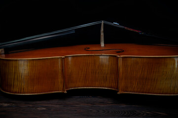 The cello lies on a wooden surface. Place for text