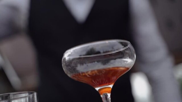 The bartender pours a thin stream of alcohol into a glass