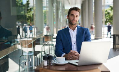 Confident young businessman working outside at a cafe table