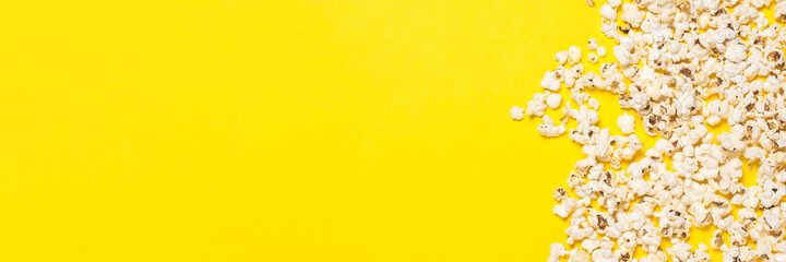 Popcorn scattered on a yellow background. Concept series, film, sports. Banner. Flat lay, top view
