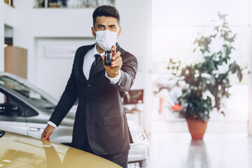 Man car dealer wearing protective medical mask on his working place