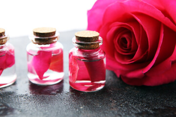 Obraz na płótnie Canvas pink rose flower and glass of bottle essential oil. spa and aromatherapy cosmetic concept.