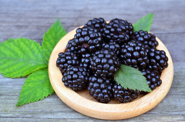 Freshly picked ripe blackberries on a wooden plate on the table.Healthy eating,vegan food or diet concept.Selective focus.