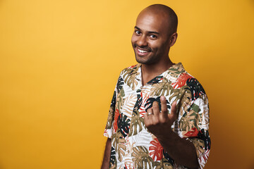Image of smiling african american guy beckoning someone
