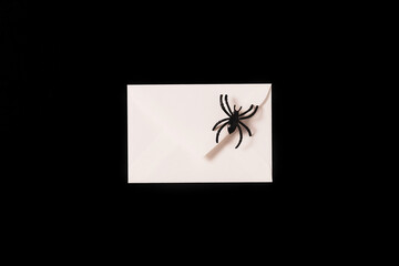 Cartoon Halloween background white envelope with black spider on black backdrop. Copy space. Flat lay style. Halloween abstract background. Dark retro black and white background.