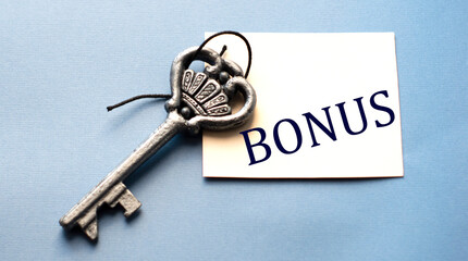 BONUS - word on white paper on a wooden background with a beautiful key