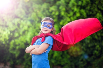 Naklejka premium Superhero kid against green background outdoor. Childhood, success and and power concept