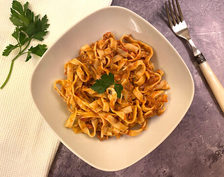 Homemade pasta boscaiola style with beef minced meat sauce, mushroom, ham, parsley and tagliatelle.