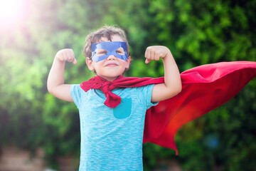 Superhero kid against green background outdoor. Childhood, success and and power concept