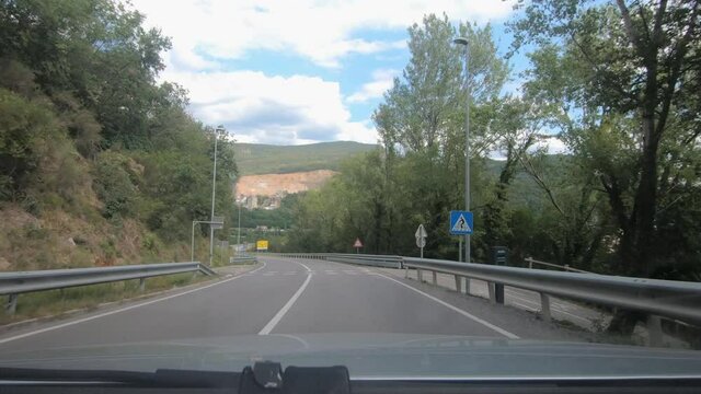 Dashboard dash cam point of view POV driving on curved countryside paved road over small town Solkan and concrete bridge over Soča river,  Slovenia. Wide angle, forward moving