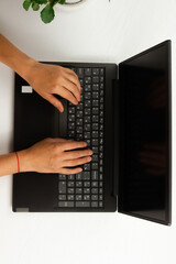 Fototapeta na wymiar female hands are typing text on laptop keyboard on white wooden table background