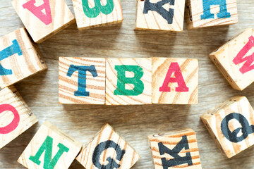 Alphabet letter block in word TBA (abbreviation of to be announced) with another on wood background