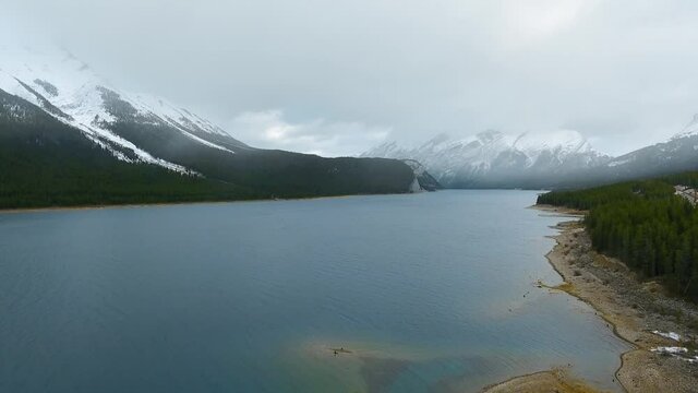 Bird's-eye view of a mirror Spray Lakes Reservoir at the foot of snowy mountains in Alberta, Canada 