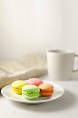 delicious delicate multicolored macaroons on a platter with a cup of coffee in the background with place for text. close-up. selective focus.