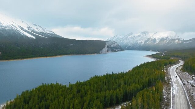 Aerial footage of the majestic nature with snow-capped mountains, immense lake and spring forest