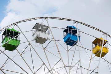 Carousel ferris wheel with colored cabins for children and adults to ride on day off.