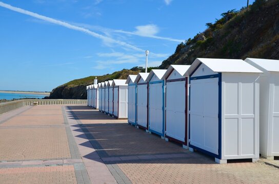 Traditional white beach cabins on the promenade near the coastal town of Granville in Normandy, France, English Channel, blue sky background, a sunny day in summer