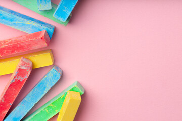 Pile of color chalks on pink background