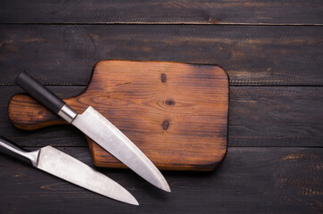 chopping board with two knives placed on an old wooden floor In the kitchen or in the restaurant used by the chef to cut vegetables or meat