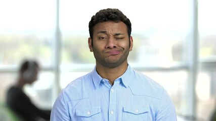 Close up Indian man making funny faces. Man making silly grimace on blurred office background.