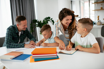 Fototapeta premium Parents helping the kids with their homework. Litlle boys learning at home..