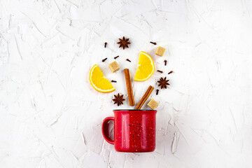 Flat lay of mulled wine ingredients. Cinnamon, orange, cardamom, clove, anise star and cup on white