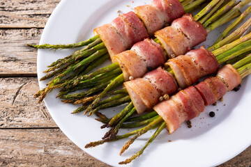 Green asparagus wrapped with bacon on wooden table
