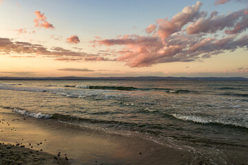 Sea surface with blue water waves under yellow and purple sunset sky.