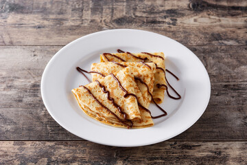 Sweet crepes with chocolate on wooden table	