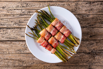 Green asparagus wrapped with bacon on wooden table. Top view